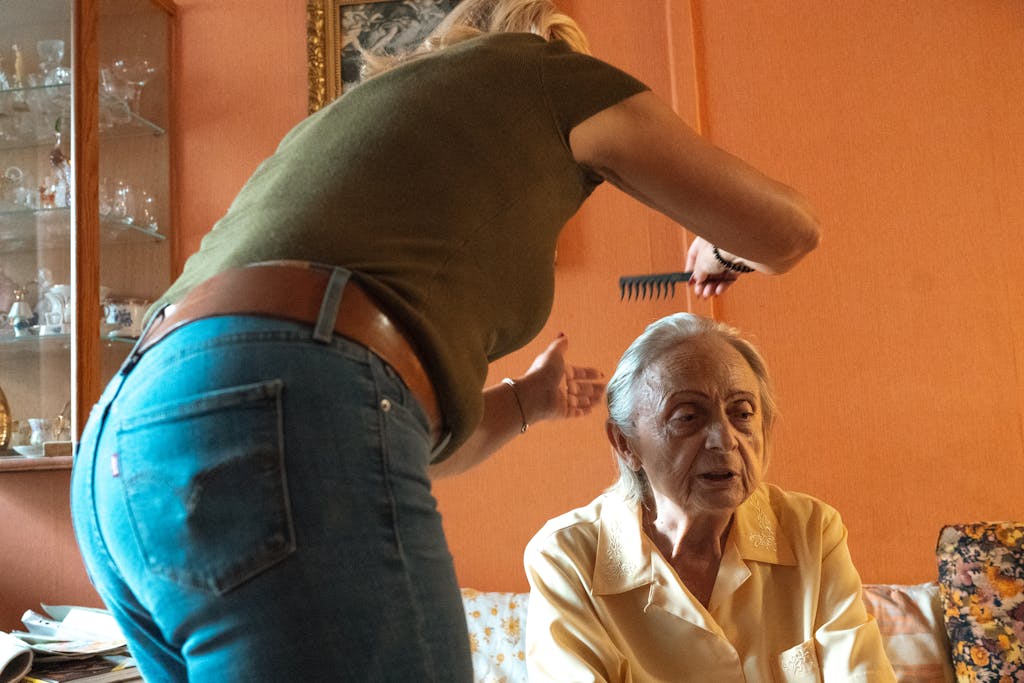A caregiver assisting an elderly woman in grooming at home in Prague.