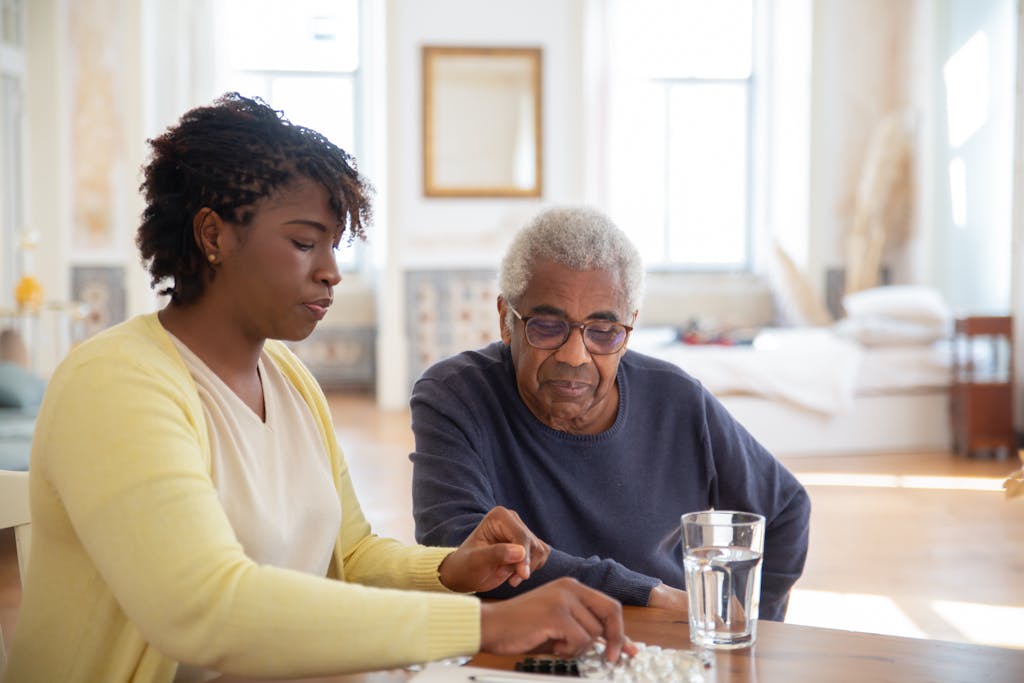 Nurse helping senior man with his medication at home, ensuring health and safety.